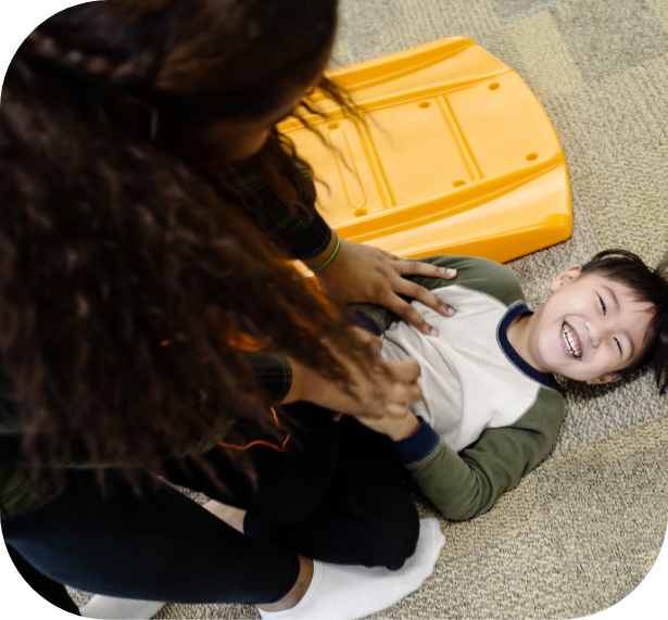 A child laughs while in play therapy with an InBloom Services professional BCBA.