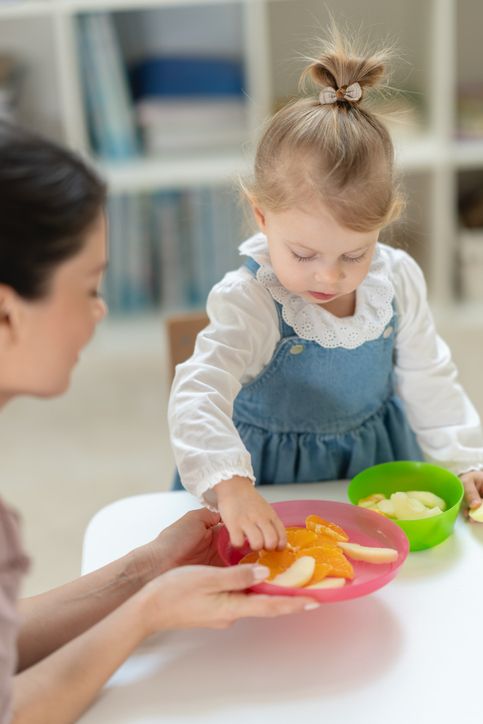 Child Selecting Fruit Slices During Snack Activity at a Classroom Table