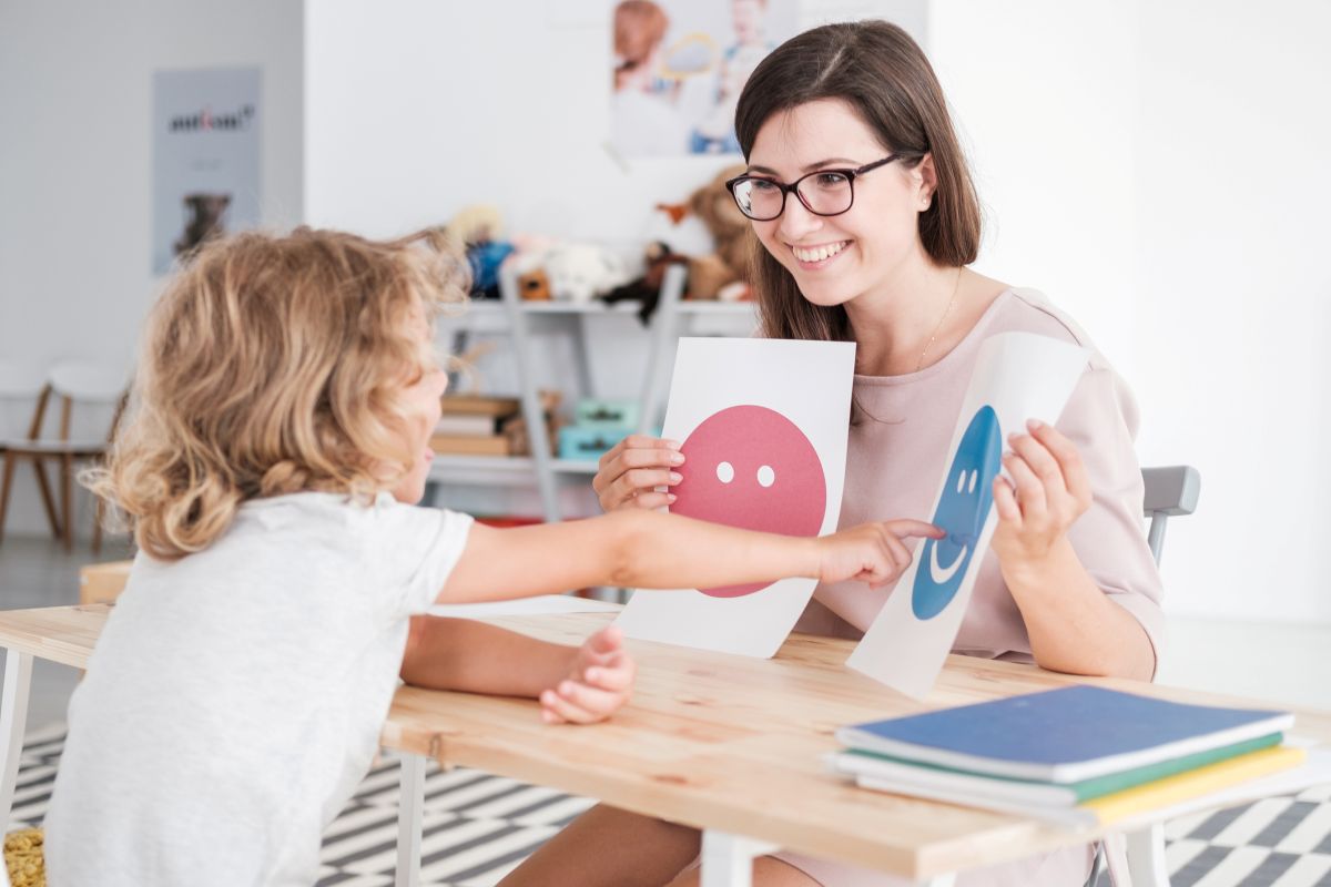 Behavior Analyst Holding Pictures During a Meeting with a Young Patient with Autism